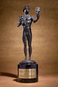 A nude bronze statue holds a mask of comedy and tragedy in each hand