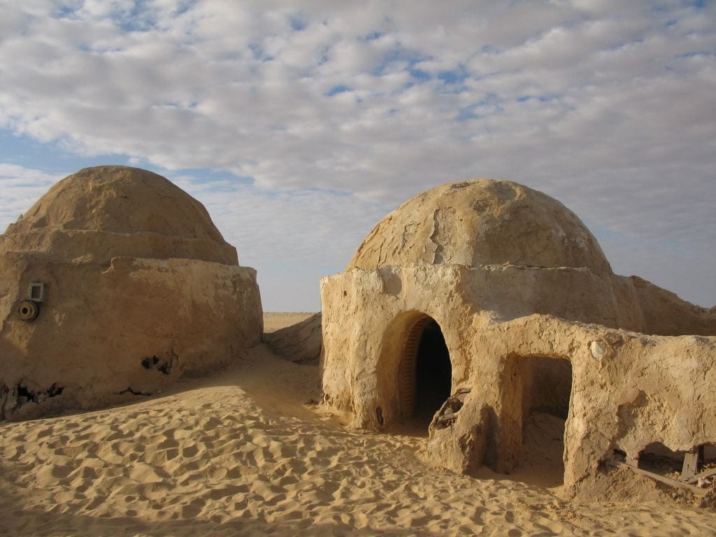 A domed hut is shown with sand creeping up the already decayed walls.