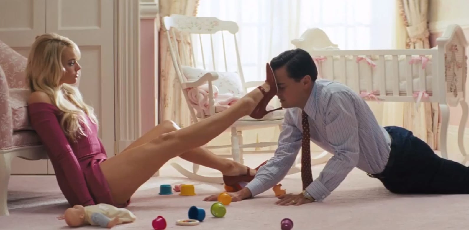 the image features a still from the movie The Wolf of Wall Street. In the image, Leonardo DiCaprio is being pushed away by a beautiful woman.