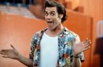 Image is a still from the movie Ace Ventura: Pet Detective. Jim Carrey is shown wearing a jazzy shirt with his hands out wide.