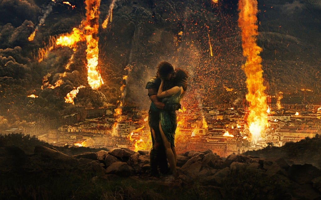 In the foreground a couple embrace and kiss standing on rubble. behind them Pompeii burns and smoulders