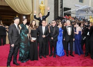 U2 posing for a photo on the red carpet at the Oscars 2014, with Benedict Cumberbatch jumping up behind them.