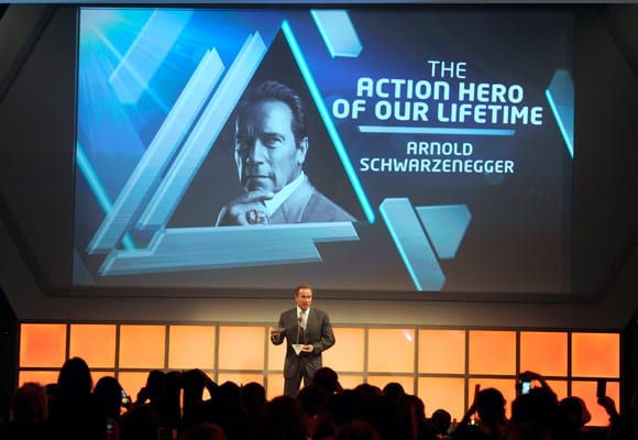 Arnold Schwarzenegger collecting his award at the Empire Awards on stage.