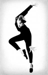 Audrey Hepburn strikes a dramatic jumping pose wearing an all black outfit