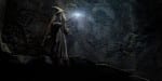 Gandalf walking through a dark cave with his staff lit in front of him.